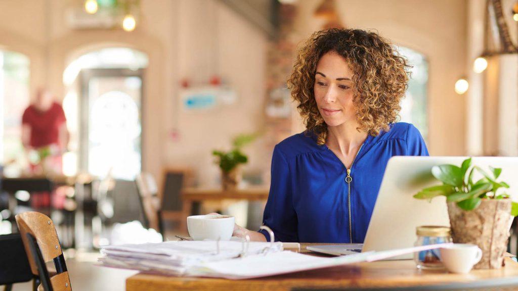 Young woman working at a desk with laptop and cup of coffee