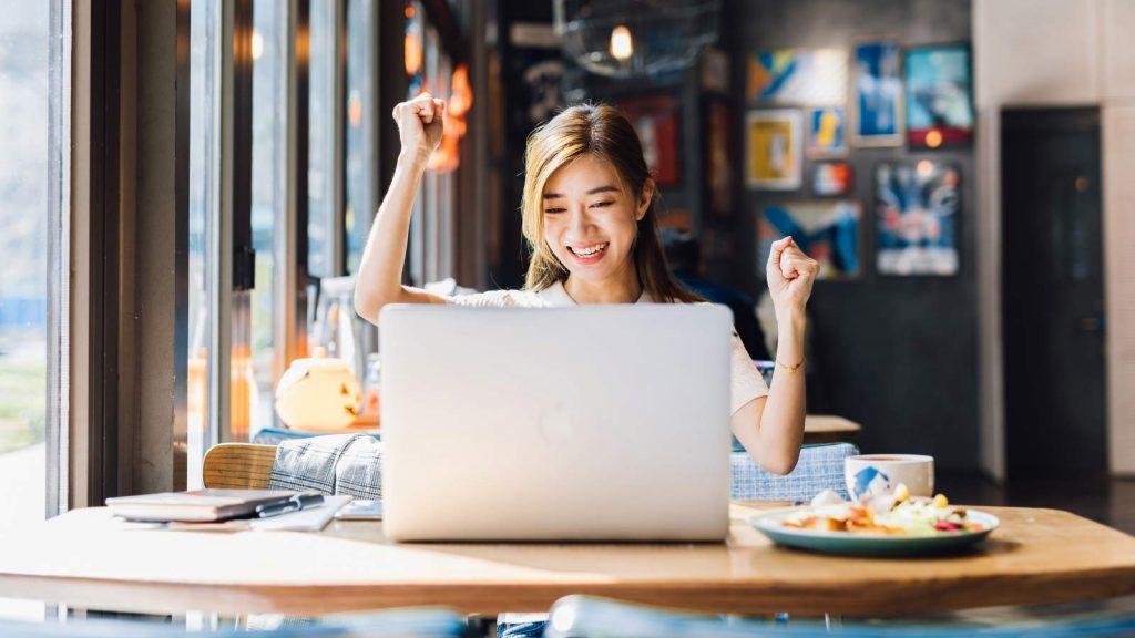 Happy young woman in from of a laptop