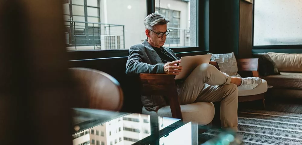 Mid-aged businessman sitting in lobby and reading